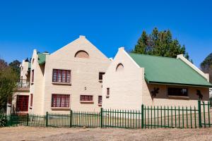a white house with a green roof and a fence at Gecko Castle in Dullstroom