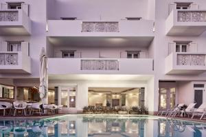 a swimming pool with chairs and a building at Oxygen Favie by GHH in Tinos