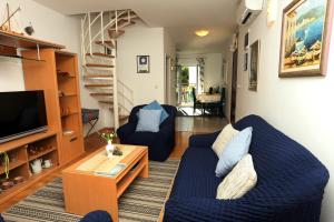 Apartments Sikirica في تروغير: غرفة معيشة مع أرائك زرقاء وتلفزيون