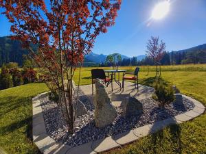 eine Terrasse mit einem Tisch, Stühlen und einem Baum in der Unterkunft Am Schwand in Grän