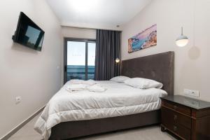Schlafzimmer mit einem Bett, einem TV und einem Fenster in der Unterkunft Tesoro Hotel Zakynthos in Planos