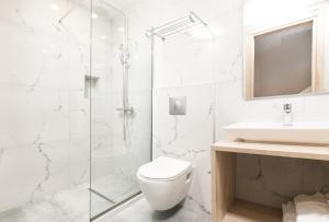 a white bathroom with a toilet and a sink at Tesoro Hotel Zakynthos in Tsilivi