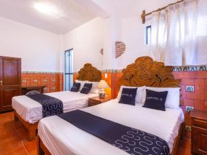 ein Hotelzimmer mit 2 Betten mit weißer Bettwäsche in der Unterkunft Capital O Posada La Casa De La Tia, Oaxaca in Oaxaca de Juárez