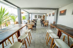 um restaurante com mesas e cadeiras de madeira e janelas em Cadiz Pousada e Lazer em Bertioga