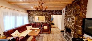 a living room with a leather couch and a stone wall at Chata Oddychovka in Demanovska Dolina
