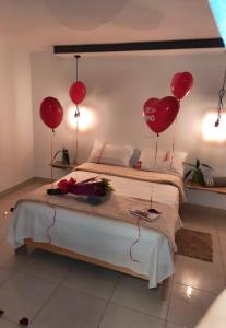 een slaapkamer met rode hartballonnen op een bed bij Hotel Neblina Calima in Calima