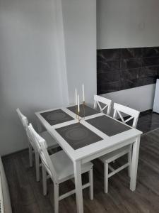 a white dining room table with white chairs and candles at Apartman San in Bugojno