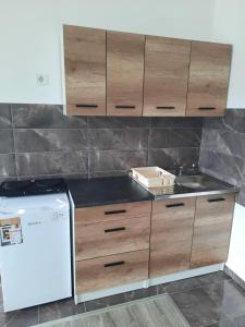 a kitchen with wooden cabinets and a sink and a refrigerator at Apartman San in Bugojno