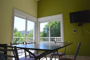 a dining room with a table and two windows at Complejo Belu in Santa Rosa de Calamuchita