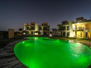a green pool in front of a building at night at Vilas na Praia Residence Canoa Quebrada CE Apartamento PÉ NA AREIA superior com 2 suítes, vista para a Praia e Dunas e com privacidade total in Canoa Quebrada