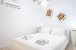 een witte slaapkamer met een wit bed en handdoeken erop bij Cave Suite by LLB Villas - Sea & Sunset View in Mykonos-stad