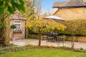 un patio con sombrilla, mesa y sillas en 2 Manor Lodge Cottages en Chipping Campden