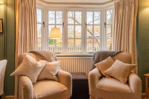 zwei Stühle in einem Wohnzimmer mit Fenster in der Unterkunft Manor Lodge Cottage in Chipping Campden + 14 Fotos