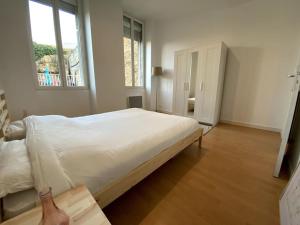 a white bedroom with a large bed and a window at - Le Saugeron - in Blaye