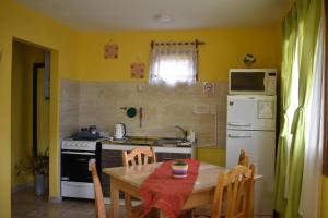 a kitchen with a table and a refrigerator and a stove at Cabañas "Las Margaritas" in Ushuaia