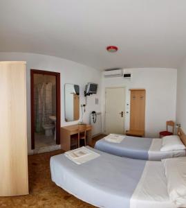 una camera d'albergo con due letti e un bagno di Albergo Anita a San Bartolomeo al Mare