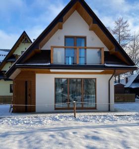 a house with a lot of windows in the snow at Domek MAYA Górska Chata - 200m od stoków Kotelnica i Termy Bania in Białka Tatrzanska