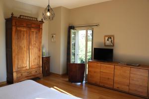 ein Schlafzimmer mit einem Bett und einer Kommode mit einem TV darauf in der Unterkunft Maison d'hôtes Marimpoey in Monein