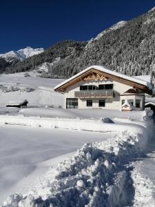 ein schneebedecktes Haus vor einem Berg in der Unterkunft Apart Stella Alpina in Pettneu am Arlberg
