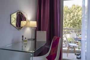 un tavolo in vetro con sedie in una camera con balcone di Hotel Chambord a Mentone