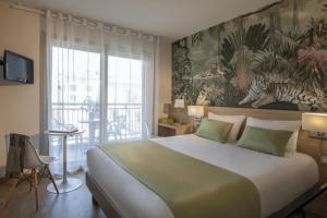 a bedroom with a large bed with a painting on the wall at Hotel Chambord in Menton