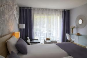 a hotel room with a bed and a large window at Hotel Chambord in Menton