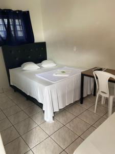 a bedroom with a bed with a table and a white sheet at Hotel Campina in Posse