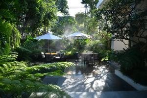 清邁的住宿－Welladee Wellness Chiang Mai，花园内提供两把遮阳伞和桌椅