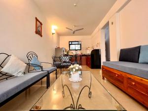 a living room with two couches and a glass table at Vistara By The Beach Goa in Marmagao