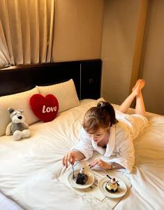 a little girl laying on a bed eating desserts at Felicity Business Hotel in Taichung