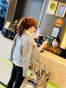 a woman wearing a mask standing at a counter in a store at Felicity Business Hotel in Taichung