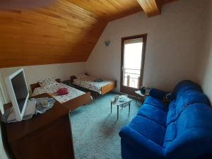 a living room with a blue couch and two beds at L'éloge de la Nature in Corps