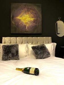 a bottle of champagne laying on a bed with pillows at Duke and Duchess Apartments and Rooms - Private in Room Hot Tub Suites in London