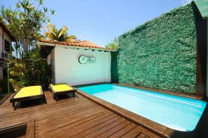 a swimming pool on a wooden deck with a green hedge at Che Lagarto Hostel Búzios in Búzios