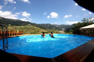 un gruppo di persone in una piscina con montagne sullo sfondo di Archontiko Metsovou Luxury Boutique Hotel a Metsovo