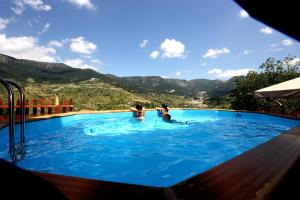 a group of people in a swimming pool with mountains in the background at Archontiko Metsovou Luxury Boutique Hotel in Metsovo