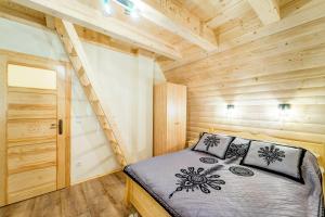 a small bedroom with a bed in a wooden cabin at Komfortowe domki na wynajem - Holiday Tatry in Poronin