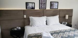 a bedroom with a large bed with three pictures on the wall at Feliccità Pousada in Extrema