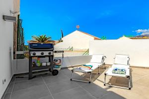 eine Terrasse mit 2 Stühlen, einem Herd und einem Grill in der Unterkunft Deluxe bungalow Perla Del Sur in Adeje