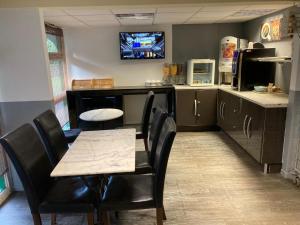 a kitchen with a table and chairs and a tv on the wall at Nouvelle Classe Hotel in Châtellerault