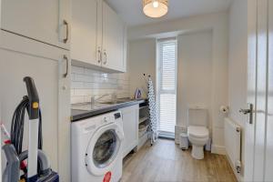 a kitchen with a washing machine and a toilet at Tunlaw Cottage in Kineton