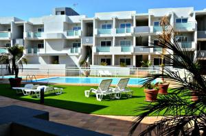 a large apartment building with chairs and a swimming pool at Corralejo Sun 103 wifi free in Corralejo