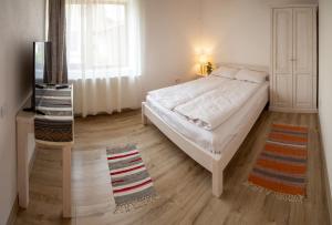 a bedroom with a white bed and a window at Otto's Guesthouse in Prejmer