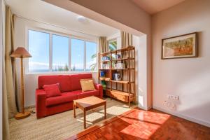 a living room with a red couch and a book shelf at Garajau House - Sunrise to Sunset Ocean View Villa in Caniço