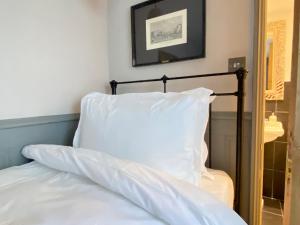 27 Brighton Guesthouse في برايتون أند هوف: سرير مع وسادة بيضاء ومرآة