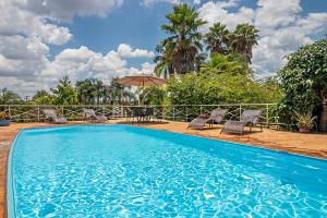 a blue swimming pool with chairs and an umbrella at Gaia Hospedagem in Brotas