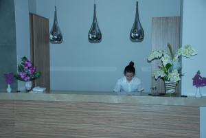 a woman sitting at a counter in a room with flowers at Begonville Beach Hotel - Adult Only in Marmaris