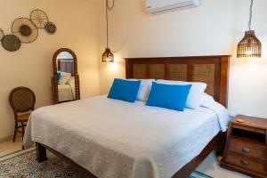 a bedroom with a bed with blue pillows and a mirror at Hotel & Hostal Boutique Casa Garza in Mérida