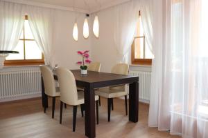 una mesa de comedor con sillas blancas y flores. en Ciasa Cir Apartments, en Badia