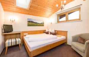ein kleines Schlafzimmer mit einem Bett und einem Stuhl in der Unterkunft Apartments Tannheim in Tannheim